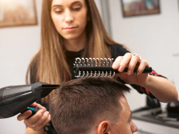 Hair salon master blow dry hair client at barber shop. Male client getting haircut by hairdresser. Hair care, beauty industry, barber concept.