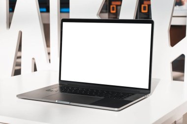 Laptop mockup with white screen in business office or shopping mall. Empty copy space, blank screen mockup. Soft focus laptop with interor background. Travel, study and office work concept.