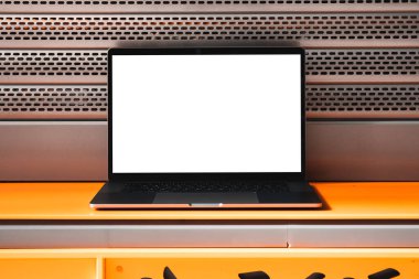 Laptop mockup with white screen in business office or shopping mall. Empty copy space, blank screen mockup. Soft focus laptop with interor background. Travel, study and office work concept.