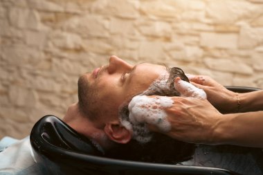 Hair salon master washing client hair at barber shop. Male client getting haircut by hairdresser. Hair care, beauty industry, barber concept.