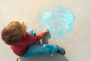 Çocuk, üzerinde dünya haritası olan bir gezegen küresi çiziyor asfalt üzerine tebeşirle boyanmış bir tebeşir. Dünya, barış günü konseri.