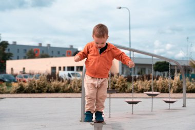 Çocuk parkında oynayan çocuklar. Çocuk dengeleme konsepti. Oğlan seyir defterinde dengesini koruyor. Çocukluk, aktif yaşam tarzı, mutluluk sembolü..