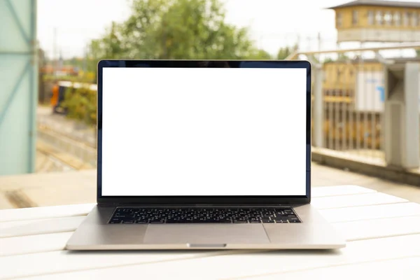 Laptop with white screen in business office or shopping mall. Empty copy space, blank screen mockup. Soft focus laptop with interor background. Travel, study and office work concept.