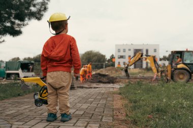 İnşaat alanı yakınında kazı yapan bir çocuk, mühendis olmayı hayal ediyor. Küçük inşaatçı. Eğitim, hayal gücü, amaç kavramı..