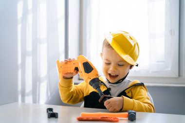Evde iş aletleriyle oynayan çocuklar, mühendis olma hayalleri. Küçük inşaatçı çocuk. Eğitim, hayal gücü, amaç kavramı. Çocuk ve talim.