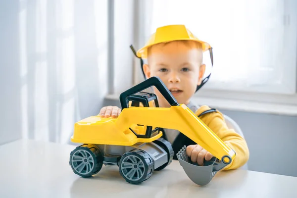 Boy with digger. Child play with excavator at home, dreams to be an engineer. Little builder. Education, and imagination, purposefulness concept.