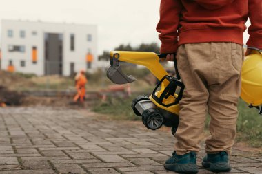 İnşaat alanı yakınında kazı yapan bir çocuk, mühendis olmayı hayal ediyor. Küçük inşaatçı. Eğitim, hayal gücü, amaç kavramı..