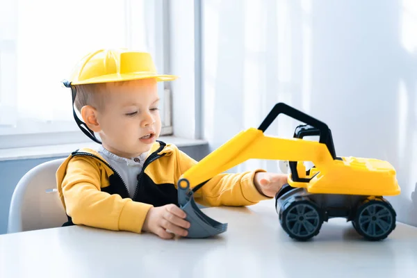 Boy with digger. Child play with excavator at home, dreams to be an engineer. Little builder. Education, and imagination, purposefulness concept.