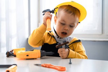 Evde iş aletleriyle oynayan çocuklar, mühendis olma hayalleri. Küçük inşaatçı çocuk. Eğitim, hayal gücü, amaç kavramı. Çocuk ve Hummer..