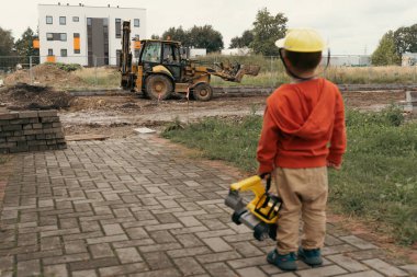 İnşaat alanı yakınında kazı yapan bir çocuk, mühendis olmayı hayal ediyor. Küçük inşaatçı. Eğitim, hayal gücü, amaç kavramı..