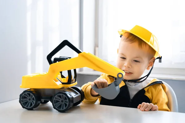 Child play with excavator at home, dreams to be an engineer. Little builder. Education, and imagination, purposefulness concept. Boy with digger.