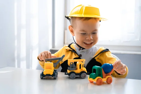 Child play with construction machinery at home, dreams to be an engineer. Little builder. Education, and imagination, purposefulness concept. Boy with digger.