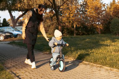 Mutlu aile annesi çocuğuna parkta bisiklet sürmeyi öğretiyor. Ağlayan çocuk korkusu, korkmuş fikir. Aile, çocukluk kavramı. Anne oğlunun bisiklete binmesine yardım et..
