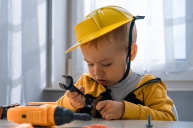 Evde iş aletleriyle oynayan çocuklar, mühendis olma hayalleri. Küçük inşaatçı çocuk. Eğitim, hayal gücü, amaç kavramı. Çocuk ve İngiliz anahtarı.