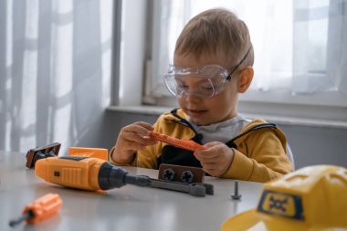 Evde iş aletleriyle oynayan çocuklar, mühendis olma hayalleri. Küçük inşaatçı çocuk. Eğitim, hayal gücü, amaç kavramı..