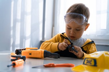 Evde iş aletleriyle oynayan çocuklar, mühendis olma hayalleri. Küçük inşaatçı çocuk. Eğitim, hayal gücü, amaç kavramı..