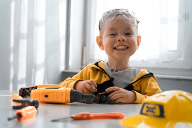 Evde iş aletleriyle oynayan çocuklar, mühendis olma hayalleri. Küçük inşaatçı çocuk. Eğitim, hayal gücü, amaç kavramı..