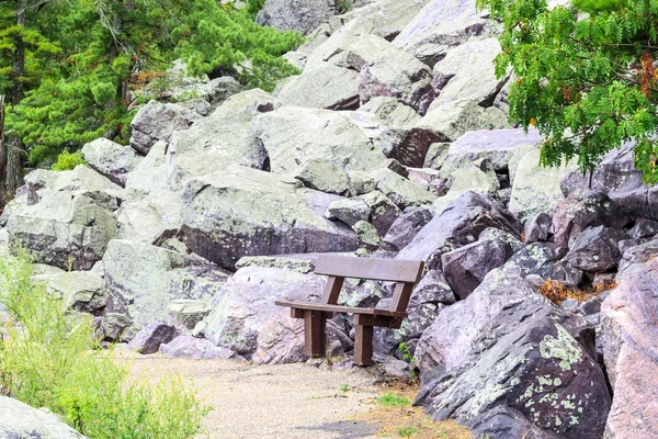 Wooden bench near large rocks — Stock Photo, Image