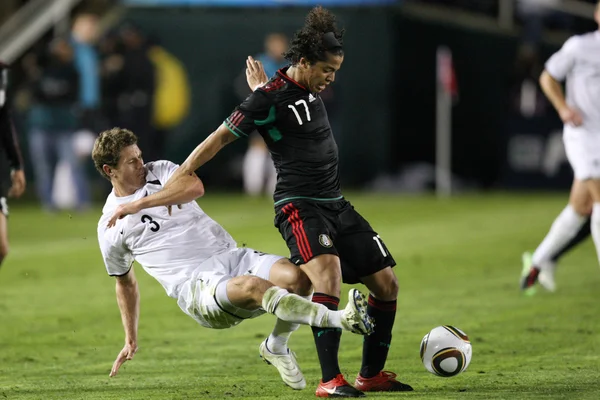 Джовани Дос Сантос удерживает Тони Лоххеда, чтобы сохранить мяч во время матча — стоковое фото