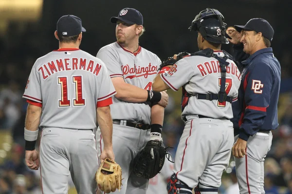 Some of the Nationals infield have a quick meeting while waiting for a relief pitcher to take the mound during the game — Stock Photo, Image