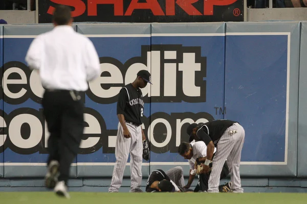 CARLOS GONZALEZ recibe atención médica después de hacer una captura profunda y estrellarse contra la pared durante el juego —  Fotos de Stock