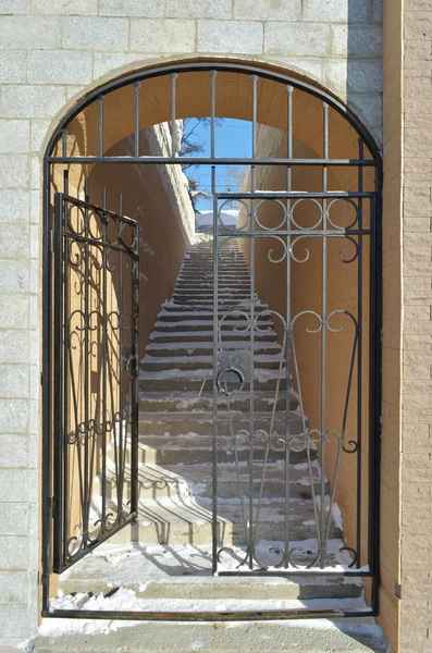 Металлическая решетка с открытыми воротами на лестнице, ведущей вверх — стоковое фото
