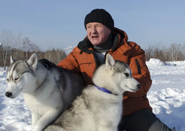 Człowiek z dwoma psami rasy husky zimą na śniegu — Zdjęcie stockowe