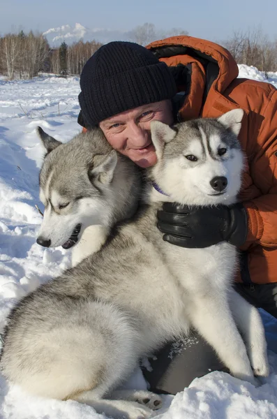 Uomo con due cani di razza husky in inverno sulla neve — Foto Stock