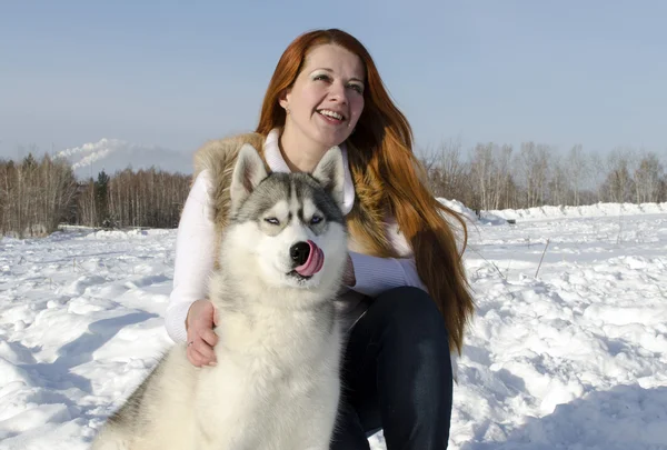 Ritratto di una bella ragazza in inverno per strada con un cane di razza husky — Foto Stock