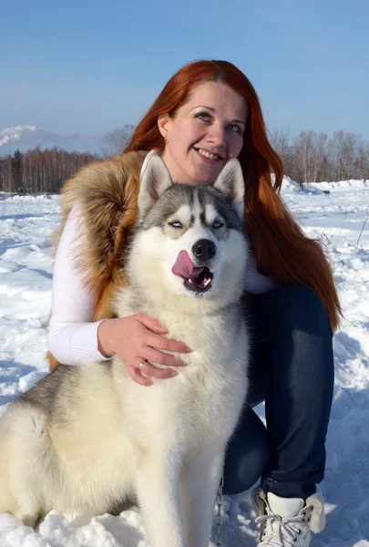 Portrét krásné mladé dívky, v zimě na ulici se psem plemene husky — Stock fotografie
