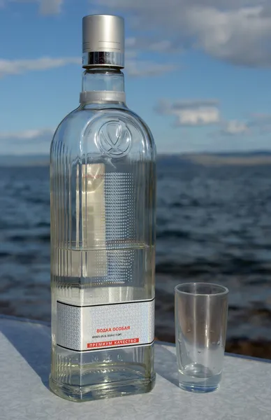 bir şişe votka ve Baykal Gölü kıyısında bir shotglass