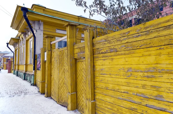 Keltainen hiutaleiksi puuaita portilla talvella kadulla — kuvapankkivalokuva
