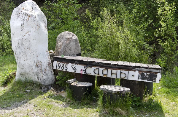 Stone, wooden couches and table with the inscription '1986 Sayan Mountains 1996' on the side of the road from Kultuk to Mondy — Stock Photo, Image