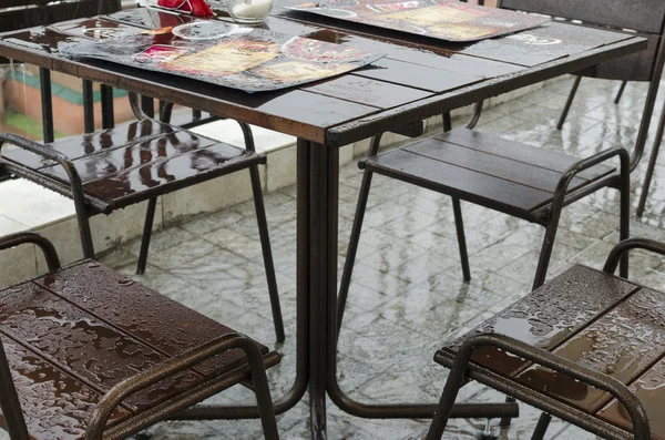 Mesa vacía y húmeda en un café al aire libre durante una tormenta —  Fotos de Stock