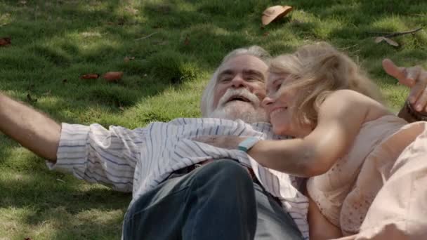 Happy grandpa and grandma with grandson playing and lying on grass in park — Stock Video