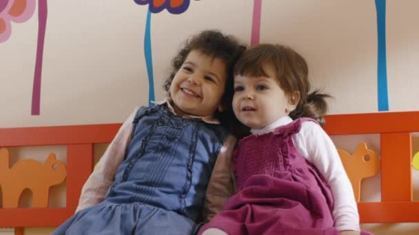 Jardin d'enfants : petites amies assises sur le banc à l'école, jouant et souriant — Video