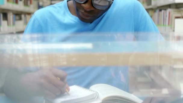 Φοιτητής κάθεται στη βιβλιοθήκη, ανάγνωση, βιβλίο και σημειώσεις. — Αρχείο Βίντεο