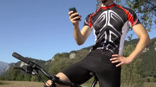 Young man riding on bicycle and text messaging on cell phone — Stock Video