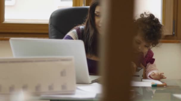 実業家でラップトップ コンピューターを自宅での作業と彼女の女の赤ちゃんと遊ぶ. — ストック動画
