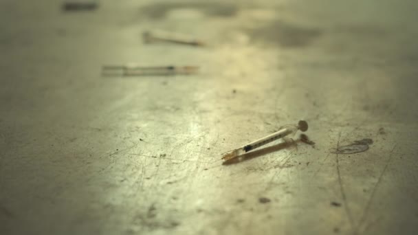 Syringes used for heroin and drugs on dirty floor — Stock Video