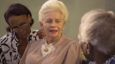 mutlu son sınıf Afro-Amerikan ve konuşmaya ve parktaki bankta oturan beyaz bayan arkadaş grubu
