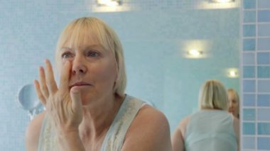 kadın güzelliğinin, yaşlı kadının yüzünde evde krem uygulamak