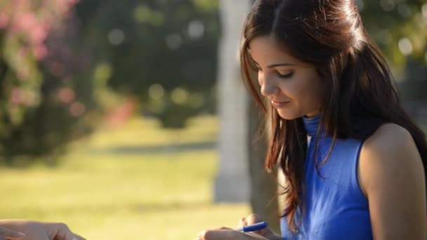 Twee vrouwelijke vrienden studie voor college examen in park — Stockvideo