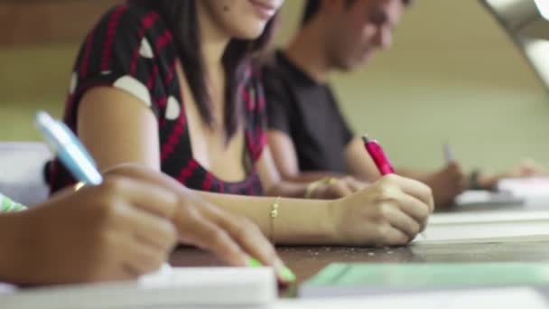 Groupe d'élèves et d'amis heureux dans la bibliothèque scolaire écrivant — Video