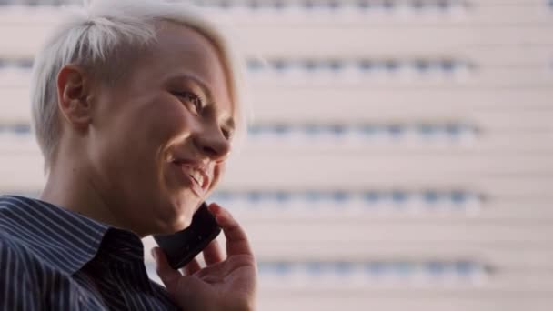 Feliz hermosa mujer de negocios rubia de pie cerca del edificio de oficinas y hablando con el teléfono móvil — Vídeos de Stock