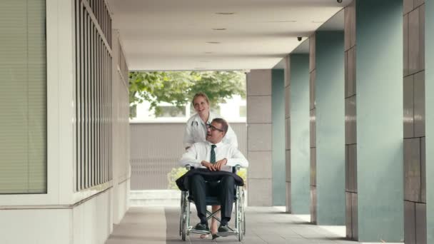 Paciente en silla de ruedas hablando con doctora en el hospital . — Vídeos de Stock