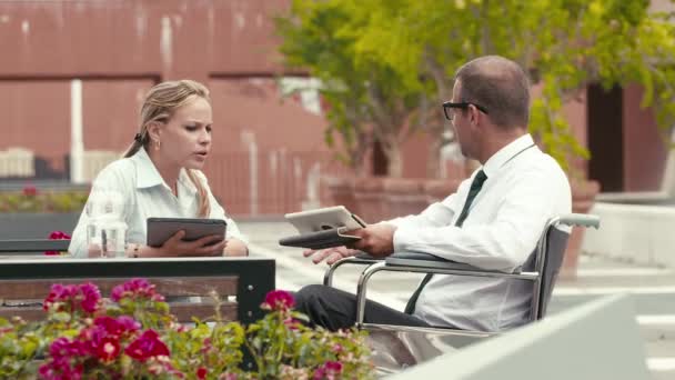 Uomo d'affari sulla sedia a rotelle che parla con una collega e utilizza un tablet digitale . — Video Stock