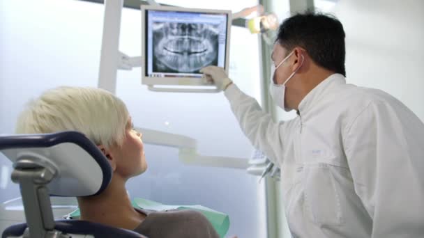 Dentista visitando jovem no estúdio odontológico — Vídeo de Stock