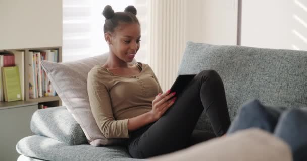 Szczęśliwa Studentka Czyta Ebook Leży Kanapie Młoda Afroamerykanka Relaksująca Się — Wideo stockowe