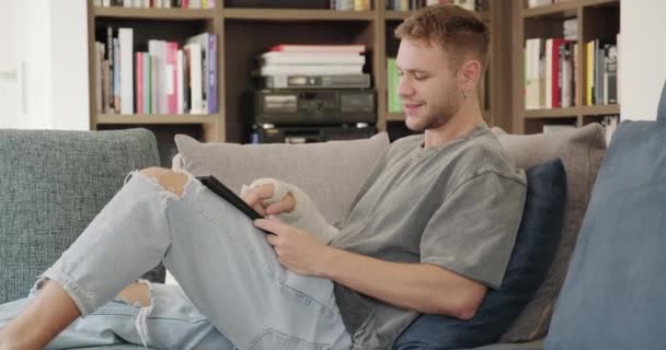 Щасливий Студент Чоловічої Статі Читає Електронну Книжку Лежить Дивані Молодий — стокове відео